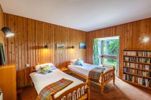 a bedroom with two beds and a book shelf at Bells View in Kippford