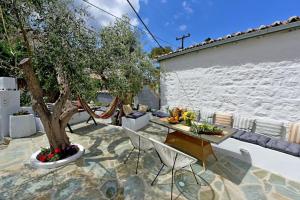 a patio with a tree and a table and chairs at Olivo II Luxury Apartment in Hydra