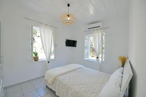 a white bedroom with a bed and two windows at Olivo II Luxury Apartment in Hydra