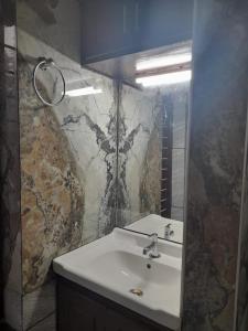 a bathroom with a white sink and a marble wall at AARONIC STAY in Varkala