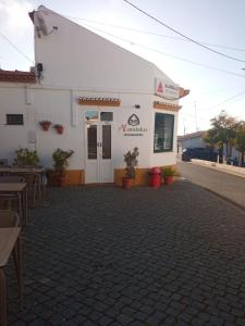 un edificio blanco con mesas y sillas delante en Casa do Rosa - Santana de Cambas, en Santana de Cambas