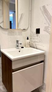 La salle de bains est pourvue d'un lavabo blanc et d'un miroir. dans l'établissement Luxury Apartment in the Cordonn Residence City Center, à Fethiye