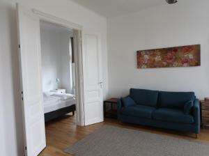 sala de estar con sofá azul y cama en Casa Nostra - Moderne lichtdurchflutete Wohnung am Augarten, en Viena