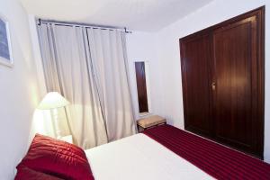 1 dormitorio con 1 cama, armario de madera y ventana en BAHIA II HomeStay by Turismar, en Salou