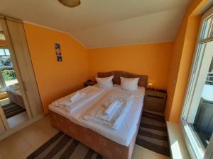 ein kleines Schlafzimmer mit einem Bett mit orangefarbenen Wänden in der Unterkunft Villa Strandnah - Ferienwohnungen in Börgerende-Rethwisch