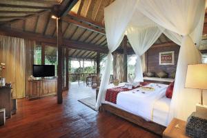 a bedroom with a canopy bed and a television at Sunia Jungle Ubud View by EPS in Ubud