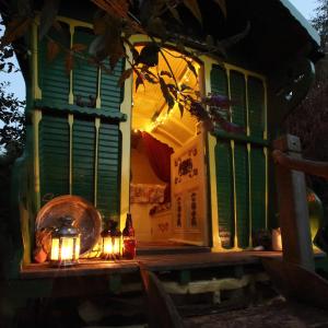 a house with lights on the porch at night at Gypsy Caravan at Alde Garden in Saxmundham