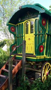 a green and yellow train sitting next to a fence at Gypsy Caravan at Alde Garden in Saxmundham