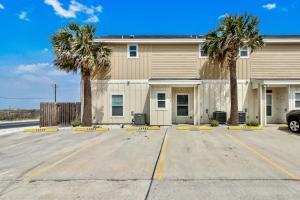 a building with palm trees in a parking lot at Chillin' Channelside in Padre Island