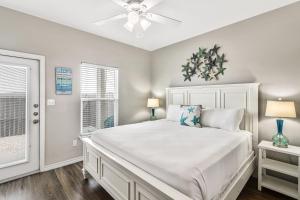 a bedroom with a white bed and two windows at Chillin' Channelside in Padre Island