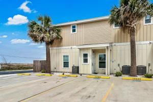 a building with palm trees in front of it at Chillin' Channelside in Padre Island