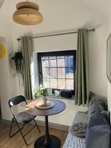 uma sala de estar com uma mesa e um sofá em Tiny guesthouse with cozy mezzanine sleeping nook em Swinderby
