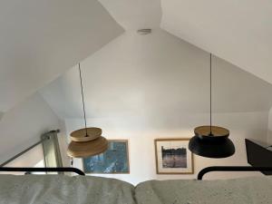 duas luzes pendentes penduradas sobre um sofá num quarto em Tiny guesthouse with cozy mezzanine sleeping nook em Swinderby