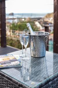 a table with two wine glasses and a bucket with a bottle at Beach Lovers Paradise in Portreath - With Sea Views & Log Burner just 100m from beach in Portreath