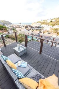 a rattan couch on a deck with a view of the ocean at Beach Lovers Paradise in Portreath - With Sea Views & Log Burner just 100m from beach in Portreath