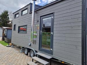 a gray tiny house on a trailer with a bench at LANE Tiny Homes in Hannover