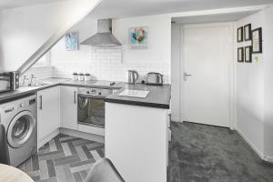 cocina blanca con fregadero y lavadora en Glencoe Holiday Apartments Whitby, en Whitby