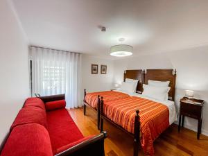 ein Schlafzimmer mit einem Bett und einem roten Sofa in der Unterkunft Quinta dos Mistérios- Turismo de Habitação in Fajã de Santo Amaro