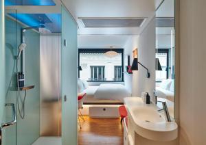 uma casa de banho com um lavatório e um quarto com uma cama em citizenM Paris Opera em Paris