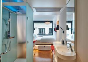 a bathroom with a sink and a bedroom with a bed at citizenM Paris Opera in Paris