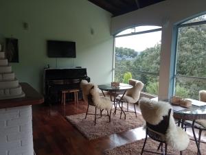 uma sala de estar com cadeiras, uma mesa e um piano em MD Luar da Montanha em Monte Verde