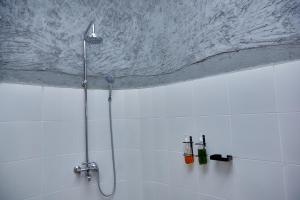 a shower in a white tiled bathroom at Kutoka Lodge in Arusha
