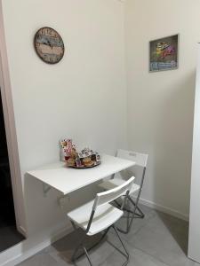 a white table and chair with a clock on a wall at FREE FLAT in Catania