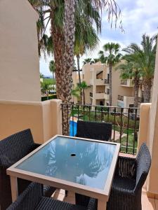 una mesa y sillas en un balcón con palmeras en Roda Golf Penthouse, en San Javier