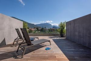 2 Stühle und ein Tisch auf einer Terrasse mit Bergen in der Unterkunft HOODY ACTIVE & HAPPINESS HOTEL in Arco