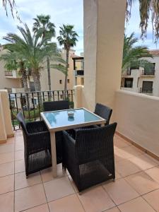 una mesa y sillas en un patio con palmeras en Roda Golf Penthouse, en San Javier