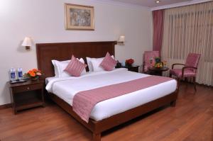 a hotel room with a large bed and two chairs at Le Lac Sarovar Portico- Ranchi in Rānchī