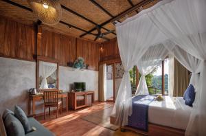 - une chambre avec un lit avec des rideaux et un bureau dans l'établissement Sacred Valley by Pramana Villas, à Tegalalang