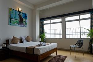 um quarto com uma cama, uma cadeira e janelas em Blissful Stay em Gangtok