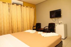 a room with a bed and chairs and a television at Mansea Beach Hotel in Kololi