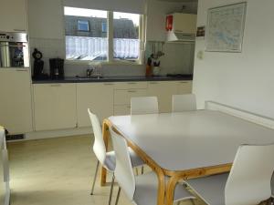 een keuken met een witte tafel en witte stoelen bij Kustverhuur, Park Schoneveld, Zeester 68 in Breskens