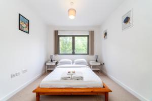 a white bedroom with two beds and two windows at Modern 3BDR Flat w large balcony, Kentish Town in London