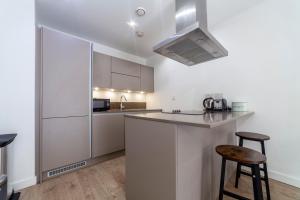 una cocina blanca con encimera y 2 taburetes en Modern 3BDR Flat w large balcony, Kentish Town en Londres