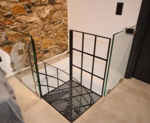 a metal gate in a room with a stone wall at Stones By Syros Bnb in Ermoupoli
