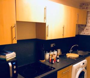 a kitchen with yellow cabinets and a sink and a dishwasher at Cunninghame 2 in Beith