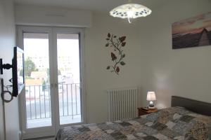 a bedroom with a bed and a sliding glass door at Le TOM de ROYAN in Royan