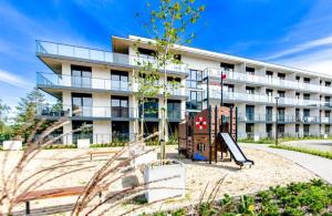 Un edificio de apartamentos con un parque infantil enfrente. en Apartament z basenem i sauną, en Dziwnów