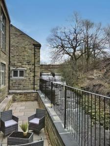 uma varanda de um edifício com cadeiras e uma ponte em The Yorkshire Hosts - The Water Mill em Haworth