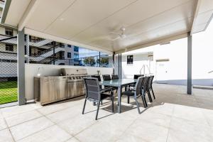 cocina abierta y comedor con mesa y sillas en Olympus Beachfront Apartments, en Gold Coast