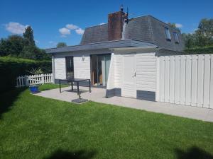 een klein wit huis met een picknicktafel in een tuin bij Hello Zeeland - Vakantiehuis Zeester 66 in Breskens