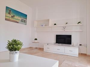 uma sala de estar branca com uma televisão de ecrã plano em Apartamentos Turísticos La Carrajolilla em Chiclana de la Frontera