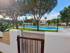 una valla blanca con una puerta frente a una piscina en Apartamentos Turísticos La Carrajolilla, en Chiclana de la Frontera