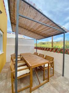 a wooden table and chairs under a roof at Casa dos Clérigos in Alcácer do Sal