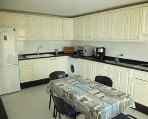 a kitchen with white cabinets and a table with chairs at Apartment Frida in Los Cristianos