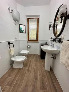 een badkamer met 2 wastafels, een spiegel en een toilet bij Appartamento Albatros in Ribolla