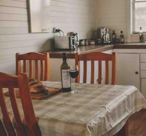 a table with a bottle of wine and a glass at Primrose Cottage in Mandurama